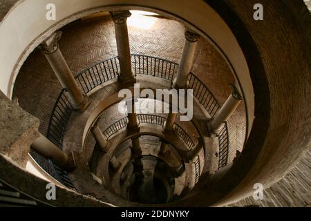 Spiral rounded ramp stairs. Into the dark, into the light. Rising up, going down. Mystic lighting. Ancient historic walls and columns. Stock Photo