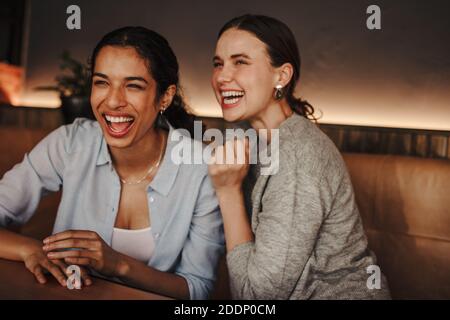 Cheerful women friends sitting in a coffee shop. Two female friends having a great time in a cafe. Stock Photo