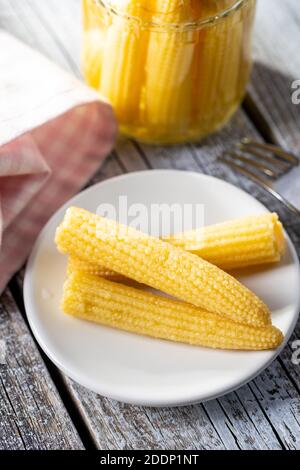 Pickled young baby corn cobs on a plate. Stock Photo