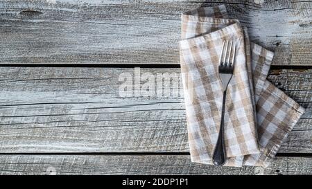 Fork and checkered napkin on wooden table. Top view. Stock Photo