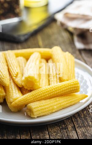 Pickled young baby corn cobs on a plate. Stock Photo