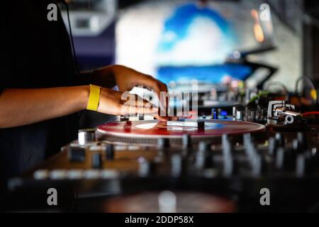 DJ girl playing music in night club with retro turntables & vinyl records.Female disc jockey scratches record on turn table player device on concert s Stock Photo