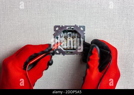 An electrician checks the voltage in the electrical network using a multimeter Stock Photo