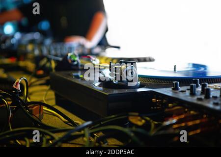 Professional dj turntable player on stage in night club.Turntables tonearm in focus.Retro analog audio equipment for disc jockey at musical festival.H Stock Photo