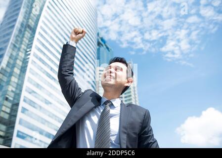 Businessman smiling and raising his fist in the air in office building ...