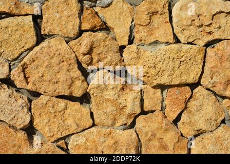 Natural wild stone castle wall cladding. Rough rock limestone wall background. Stock Photo