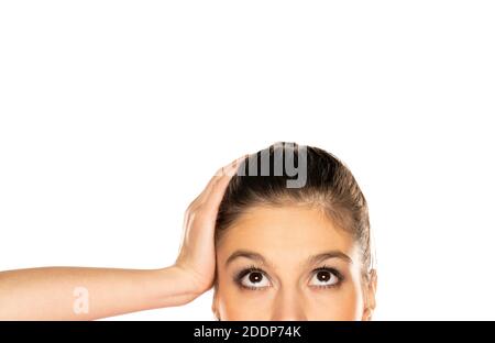 Half portrait of young puzzled woman , looking up on white background Stock Photo