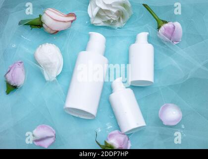 Top view of mock-up of white squeeze bottle plastic tube and roses on a blue background. Bottle for branding and label. Luxury cosmetic. Copy space, F Stock Photo