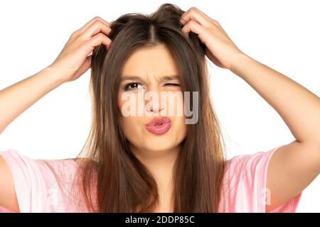 portrait of young nervous woman scratches her head on white background Stock Photo