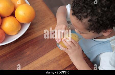 child drinking a glass of orange fruit juice promoting healthy eating stock photo Stock Photo