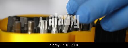 Hand in rubber glove holds screwdriver near box with tools closeup Stock Photo