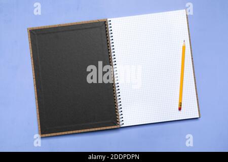 Pencil on blank squared notebook opened on first page on purple surface, high angle view Stock Photo