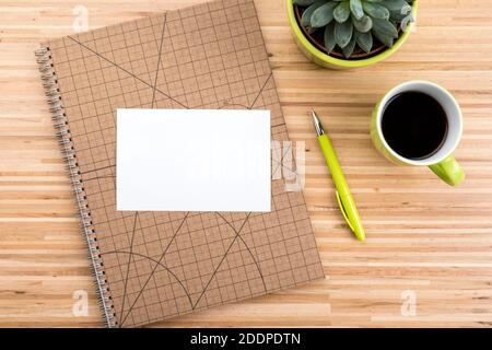 Wooden desk with ring binder, coffee cup, potted succulent plant  and copy space on blank paepr Stock Photo