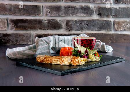 Omelette with salmon on slate plate and cup of latte Stock Photo