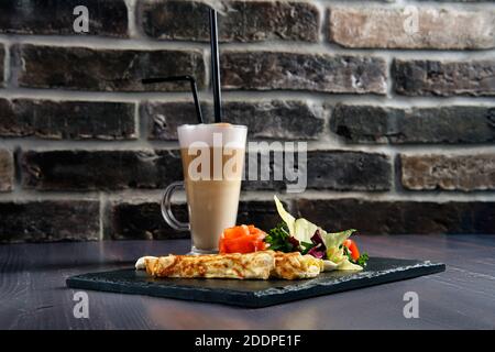 Omelette with salmon on slate plate and cup of latte Stock Photo