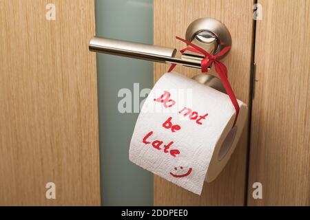 Toilet paper roll tied to door handle, big plan. Joke on the lack of hygiene in the restroom Stock Photo