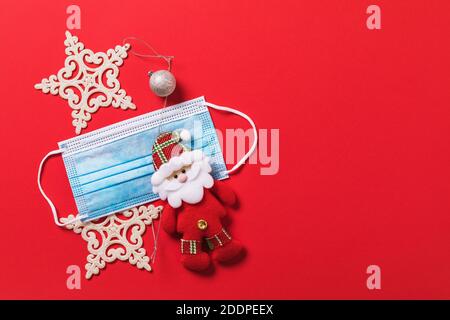 Christmas decorations and medical mask on a red background with copy space. Concept on the topic of quarantine during the holidays due to the coronavi Stock Photo