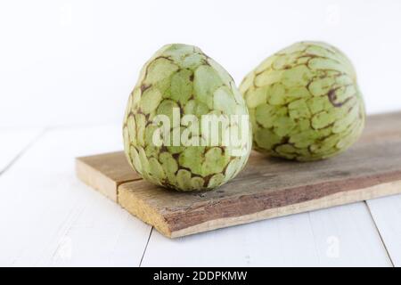 Two custard apples on a cut board against white background Stock Photo