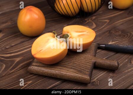 Delicious ripe persimmon fruit on brown wooden background Stock Photo