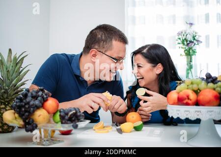 Happy married couple eating fruits. Healthy activity, indoors, cold prevention Stock Photo