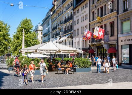 People strolling or having a drink at the terrace of a Starbucks Coffee in the place de Longemalle in Geneva, in front of the hotel de la Cigogne. Stock Photo