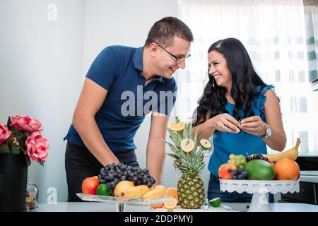Happy married couple preparing fruit salad. Healthy activity, indoors, cold prevention Stock Photo