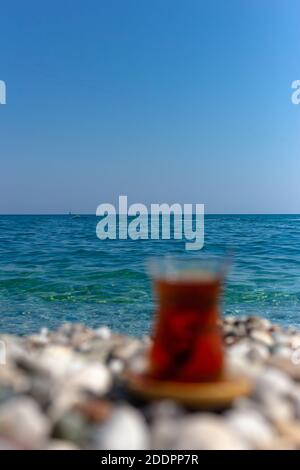 Tea in a glass out of focus on the background of the sea. Armudu.  Stock Photo