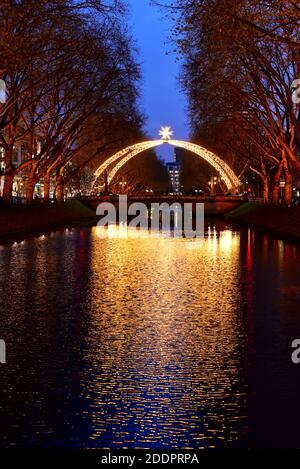 Traditional Christmas arc at Königsallee with reflection of the light in the city canal. Stock Photo