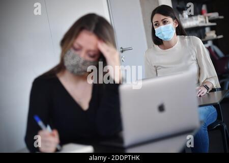 Themed picture CoWorking Space. Two young women sit at individual tables and wear face masks and masks. You are working on your laptop in a CoWorking office on November 22nd, 2020. Alternative to home office. Coworking is a development in the area of 'new forms of work'. Freelancers, smaller startups or digital nomads work in mostly larger, relatively open spaces and can thus benefit from each other. You either work independently in different companies and projects or develop projects together with other coworkers. MODEL RELEASED! | usage worldwide Stock Photo
