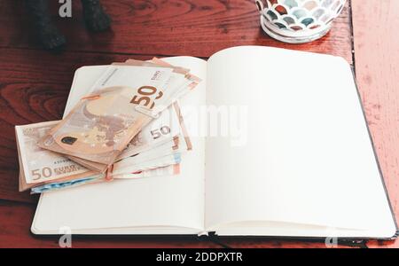 bundels of money on open notebook against old wooden desk Stock Photo
