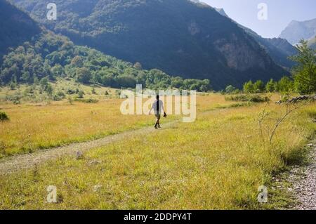 An isolated man is walking on an hike trail in a plain under the Sibillini Mountains (Marche, Italy, Europe) Stock Photo