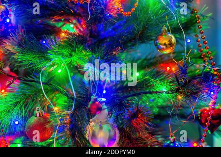 Close up of colorful Christmas lights decorating a tree, baubles hanging Stock Photo