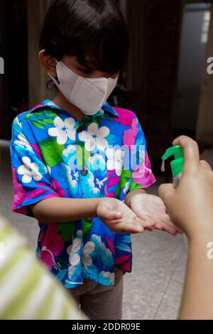 Southeast Asian boy using liquid gel hand sanitizer. Protection against infectious virus Hygiene and healthy lifestyle. Stock Photo