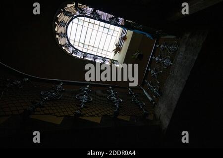 Destroyed staircase with a metal railing nostalgically illuminated by the upper window Stock Photo