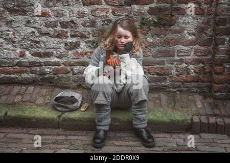 Deventer, Netherlands, December 15, 2018: Little girl begging on the street during the Dickens Festival in Deventer Stock Photo