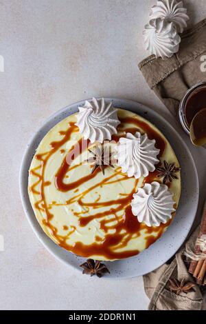 Vanilla cheesecake with carrot cake crust served with salty caramel topping and meringue, light concrete background. Selective focus. Stock Photo