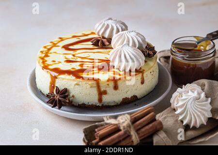 Vanilla cheesecake with carrot cake crust served with salty caramel topping and meringue, light concrete background. Selective focus. Stock Photo