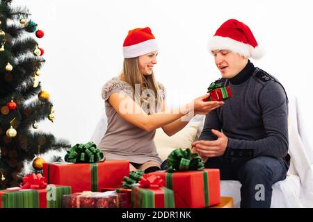 Couple exchanging gifts, in the foreground a mountain of red and green gifts, white background Stock Photo