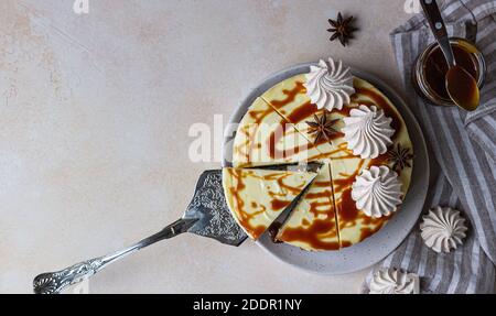 Vanilla cheesecake with carrot cake crust served with salty caramel topping and meringue, light concrete background. Selective focus. Stock Photo