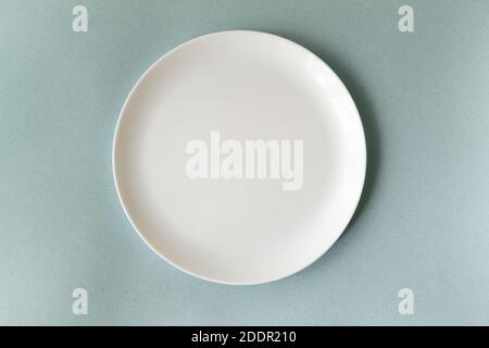 Empty white plate on a blue background. Horizontal orientation. Top view. Copy space. Stock Photo