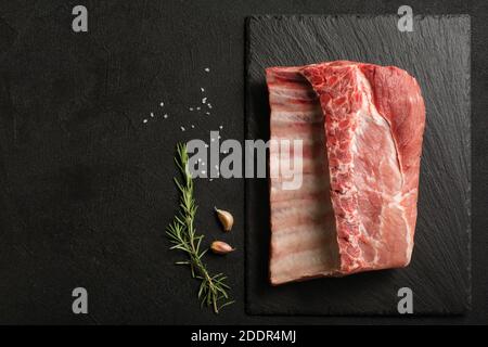 Fresh uncooked pork ribs on round cutting board with cherry tomatoes ...