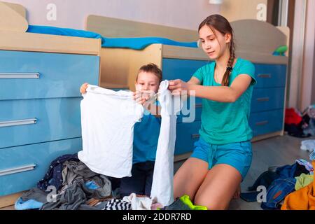 Happy children folding clothes in thier messy bedroom Stock Photo