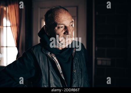 Elderly man looking through the window, pensive, worried. Stock Photo