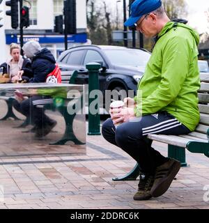 London UK, November 26 2020, Elderly Man Sitting Outside Drinking Takeaway Coffee Alone During Covid-19 Lockdown Stock Photo
