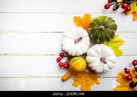 Autumn side border of white pumpkins and autumn leaves over a rustic white wood background, top view Stock Photo