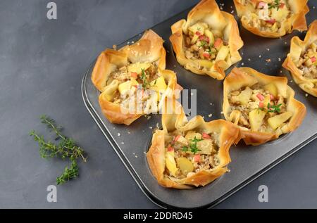 Phyllo dough with cheese, apple and nuts in muffin pan on grey background. Top view. Stock Photo