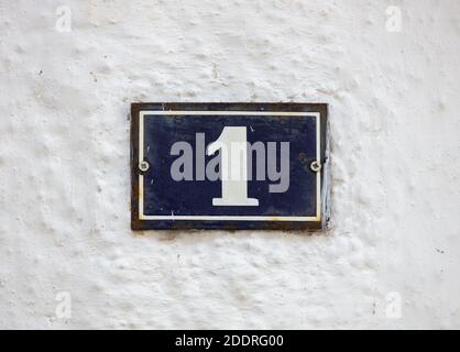 Street number one. Digit 1 on metal vintage plate mounted on whitewashed wall. Traditional house address Stock Photo