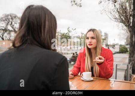 Two angry friends discussing while sitting at coffee shop. Stock Photo