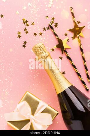 https://l450v.alamy.com/450v/2ddrhn4/shiny-paper-straws-for-cocktail-golden-stars-glitter-confetti-bottle-of-champagne-wine-as-a-gift-with-satin-bow-on-pastel-pink-background-top-view-2ddrhn4.jpg