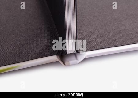 Open, high quality photo book with hardback, in colorful cover on white studio background. Close up, copy space Stock Photo